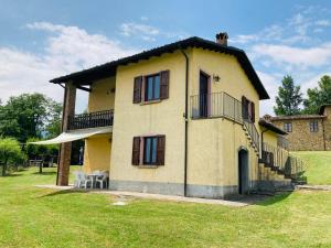 a yellow house with a balcony and a grass yard at Agriturismo Tramonti in Castiglione di Garfagnana