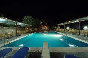una piscina notturna con tavoli e sedie di Lalloudes Seaside Accommodation a Éxo Nímfion
