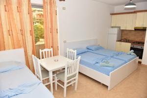 a bedroom with two beds and a table and a kitchen at Vila Namiku in Durrës