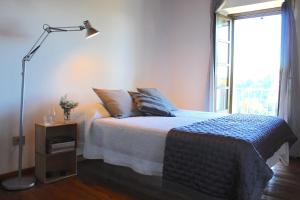 a bedroom with a bed with a lamp and a window at AMAZING LANGHE AND MONFERRATO | House with garden in Calamandrana
