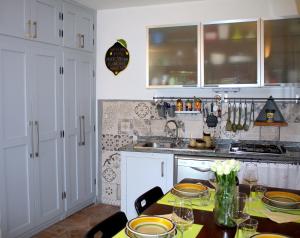 una cocina con armarios blancos y una mesa con sillas. en AMAZING LANGHE AND MONFERRATO | House with garden en Calamandrana