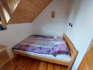 małe łóżko w pokoju z drewnianą podłogą w obiekcie Domki nad jeziorem - Posiadłość Nad Zatoką w Rynie