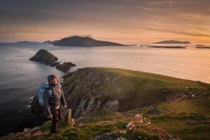 CloghaneMount Brandon Hostel的站在悬崖上俯瞰大海的人