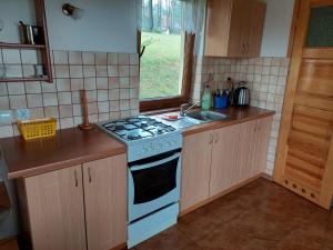 a kitchen with a white stove and a sink at Domki nad jeziorem - Posiadłość Nad Zatoką in Ryn