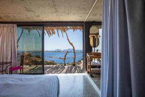 1 dormitorio con vistas al océano a través de una ventana en Muar Suites en Agios Pavlos