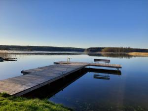 a dock with two benches on a lake at Nad Zatoką pokoje z widokiem na jezioro in Ryn