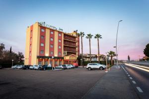 a building with cars parked in a parking lot at Hotel Zeus in Merida