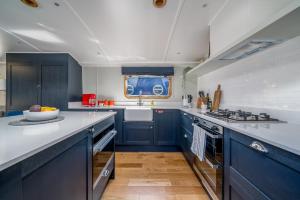 a large kitchen with blue cabinets and a sink at ALTIDO Stylish barge near Canary Wharf in London