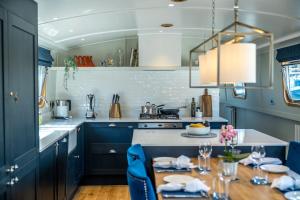 a kitchen with blue cabinets and a table with blue chairs at ALTIDO Stylish barge near Canary Wharf in London