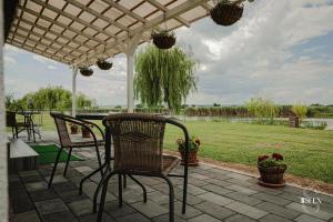 een patio met stoelen onder een witte pergola bij Bungalouri Balta Paradisul Pescarilor in Pufeşti