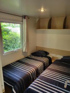 two beds in a small room with a window at Camping Ixtila mobilhome in Larrau
