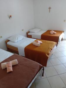 drie bedden in een kamer met bruin en wit bij Pansion Nadja in Međugorje