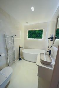 a white bathroom with a tub and a toilet at Hotel Coroana in Tîrgu Frumos