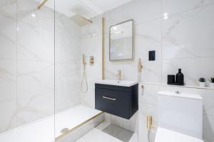 a white bathroom with a sink and a shower at Luxury 1 Bedroom Apartment in Central London in London