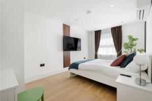 a white bedroom with a bed and a television at Luxury 1 Bedroom Apartment in Central London in London