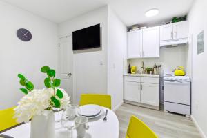 a white kitchen with a white table and yellow chairs at Gorgeous Manhatten Gem in New York