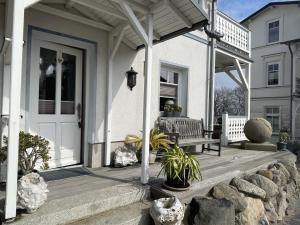 un porche de una casa blanca con un banco en Villa Seestern - Ferienhaus mit Meerblick, en Sassnitz