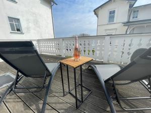 a bottle on a table on a balcony with two chairs at Villa Seestern - Ferienhaus mit Meerblick in Sassnitz +10 photos