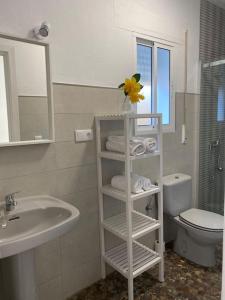 a bathroom with a sink and a shelf with towels at Bonita casa en Bolonia in Bolonia