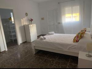 een witte slaapkamer met een bed en een raam bij Bonita casa en Bolonia in Bolonia