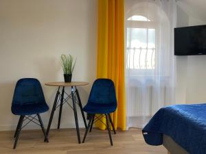 sypialnia z 2 niebieskimi krzesłami, stołem i łóżkiem w obiekcie Ośrodek Wczasowy Magnat w Łebie