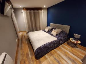Schlafzimmer mit einem Bett mit blauen Wänden und Holzböden in der Unterkunft L’Ombragée Au Doux Refuge in Courtonne-la-Meurdrac