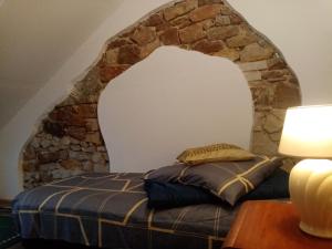 uma cama num quarto com uma parede de pedra em Agroturystyka Camp4x4 em Nosów