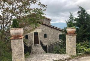 a stone house with two large pots on the gate at Antica dimora Palazzo Rossi in Marsico Vetere