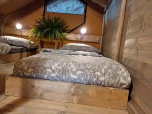 a bed in a room with a wooden wall at Glamping Debbiare in Riparbella