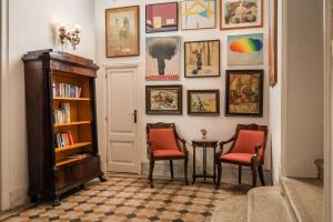 a hallway with two chairs and a book shelf and paintings at Hotel Medium Romantic in Sitges