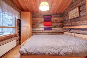 1 dormitorio con 1 cama en una cabaña de madera en Kelohonkahuoneisto Käkriäinen A, en Suomutunturi