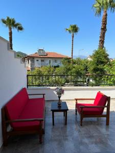 two chairs and a table on a patio with palm trees at Villa Misli - red/ green in Dalyan