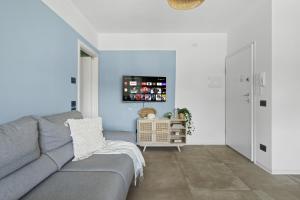 a living room with a gray couch and a tv at Casa al Lago di TSS' - Ampio Giardino Fronte al Lago - Perfetto per Famiglie e Gruppi a Calceranica al Lago in Calceranica al Lago