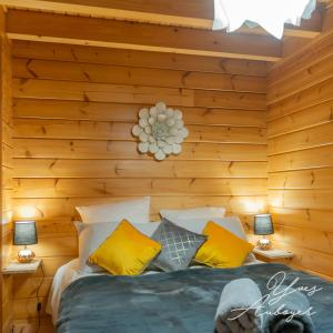 una camera da letto con pareti in legno e un letto con cuscini gialli di Chalet La Calougeotte avec jardin, sauna et spa intérieur privatif a Le Ménil