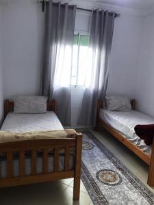 two beds in a room with a window at Appartement Familial Proche Aeroport Bab Andalous Tanger in Tangier
