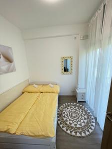 a bedroom with a bed with a yellow blanket on it at Gyöngybagoly Apartman in Balatonberény