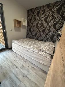 a bed in a room with a wall at Domek Apartamenty Sun House in Boszkowo