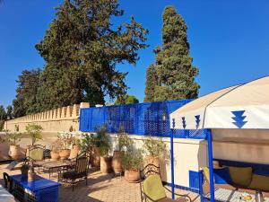 une terrasse avec des chaises, une clôture bleue et des arbres dans l'établissement Dar Al Kounouz, à Marrakech