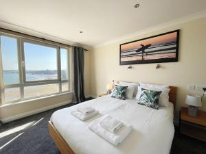 a bedroom with a large white bed with a large window at Chy Lowen in Newquay