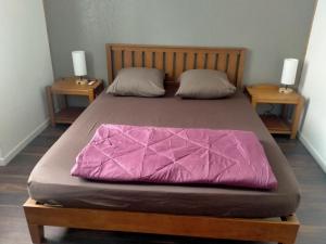 a bed with a pink comforter on top of it at Le Grand Saint Antoine in Saint-Jean-de-Maurienne