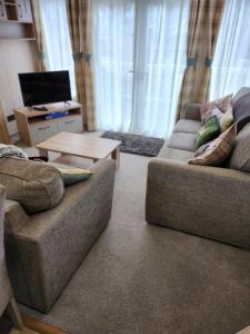 uma sala de estar com um sofá e uma mesa em luxury new 3 bed caravan with stunning sea view on private beach in Thorness bay em Porchfield