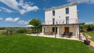 ein großes weißes Haus mit Terrasse und grünem Rasen in der Unterkunft Villa Saini with Sea View in Dajla