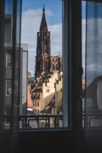 einen Blick aus einem Fenster eines Gebäudes mit einem Uhrturm in der Unterkunft Maison Rouge Strasbourg Hotel & Spa, Autograph Collection in Straßburg