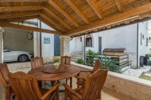 un patio con una mesa de madera y sillas y un coche en Apartments Gabi, en Pula