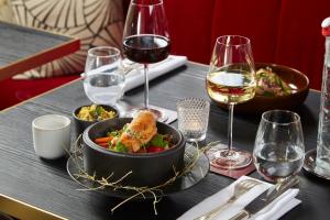 un tavolo con una ciotola di cibo e bicchieri di vino di Maison Rouge Strasbourg Hotel & Spa, Autograph Collection a Strasburgo