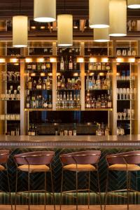 a bar with brown chairs and a shelf of alcohol at Maison Rouge Strasbourg Hotel & Spa, Autograph Collection in Strasbourg