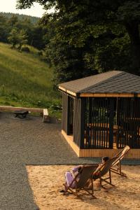 deux enfants assis sur des chaises devant un bâtiment dans l'établissement Campo Resort, à Duszniki-Zdrój