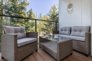 a patio with wicker chairs and a table on a deck at Wellness Resort & SPA Dziwnów Apartments with Parking by Renters in Dziwnów