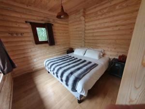una camera con un letto in una baita di tronchi di Les Lodges Du Reynou a Le Vigen