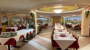 un comedor con mesas blancas y manteles rojos y blancos en Hotel Saxl, en Campo di Trens